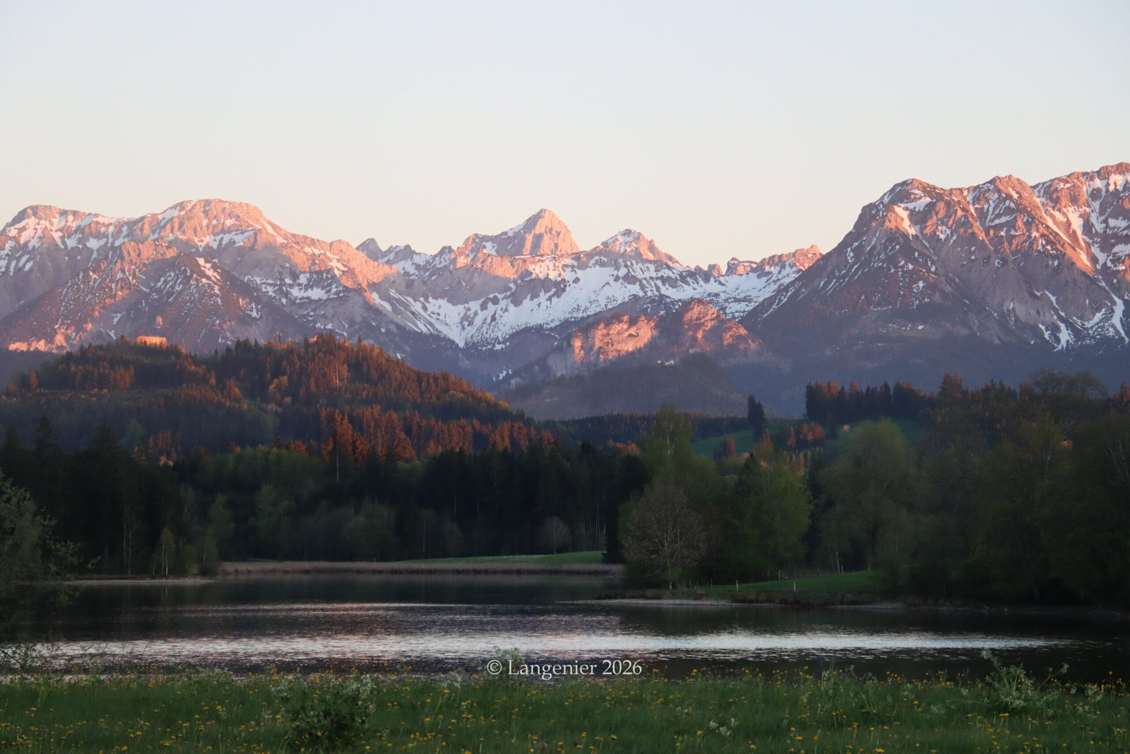Alpenglow on snow-capped Allgäu Alps reflected over a tranquil lake near Nesselwang, Bavaria