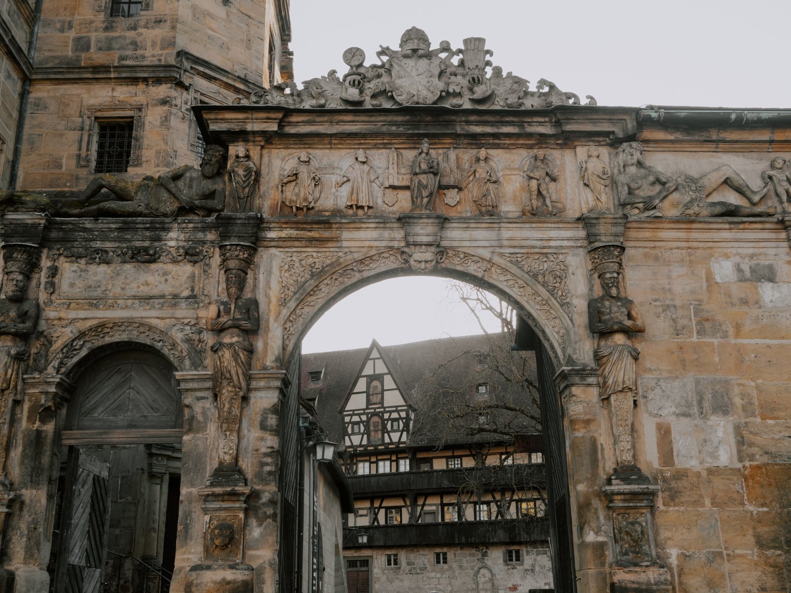 Ornately carved stone archway at the Alte Hofhaltung in Bamberg with statues and imperial coat of arms