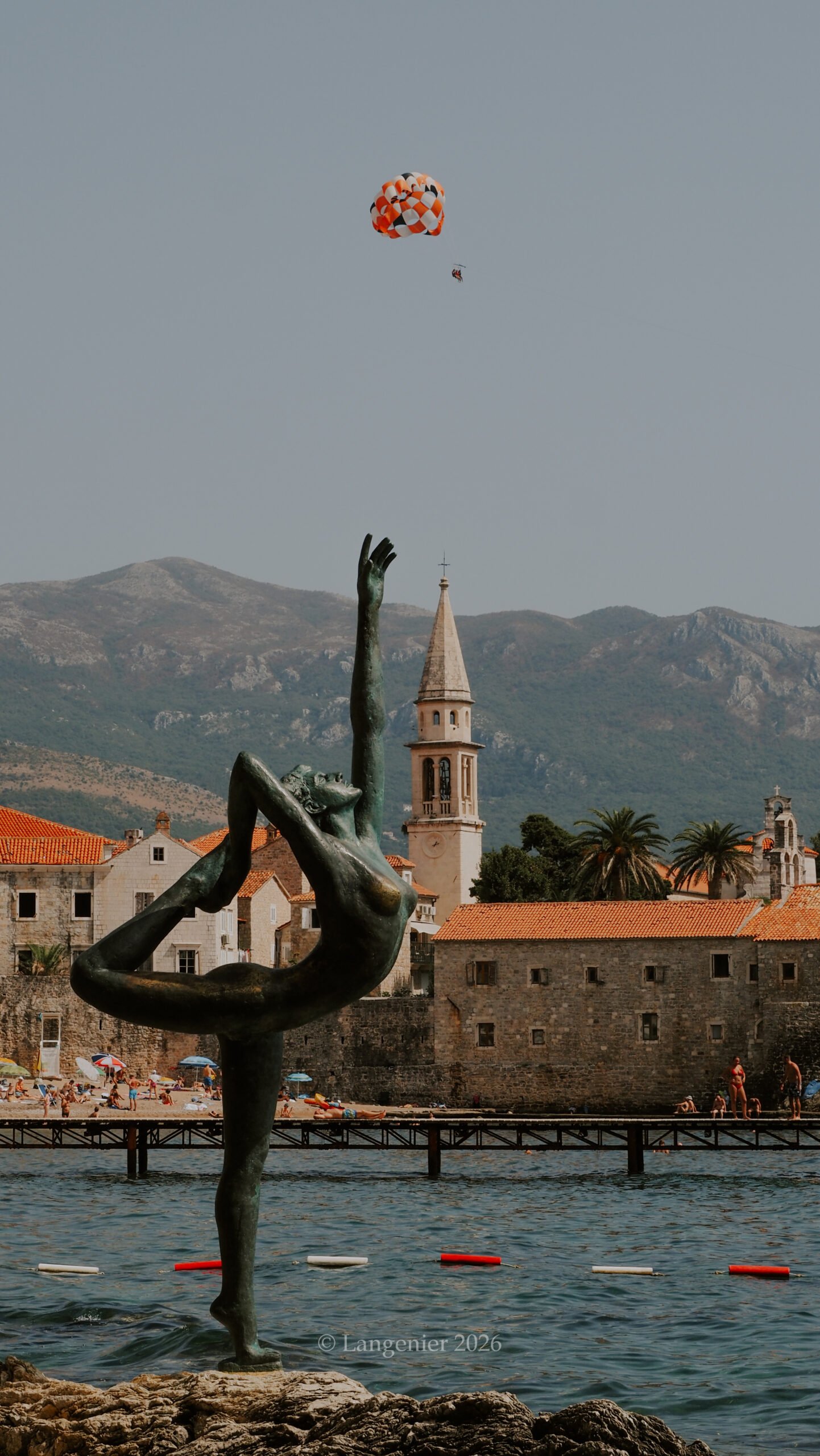 Bronze dancer statue on the rocks facing Budva's old town and Adriatic Sea, Boka Bay, Montenegro