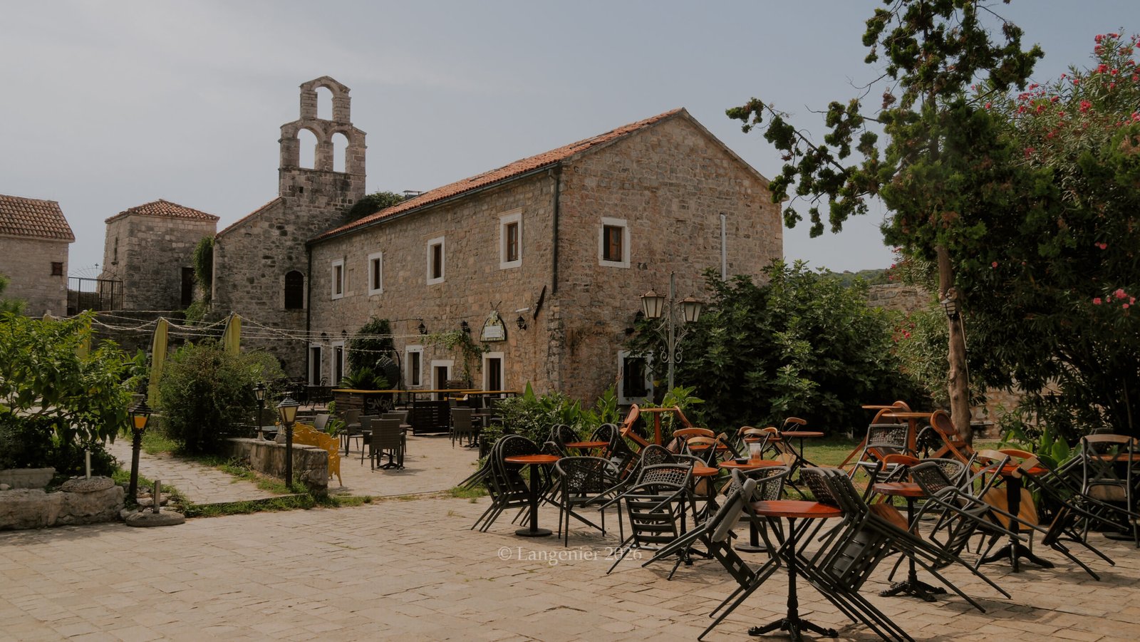 Ruined stone church bell tower and courtyard cafe in Budva old town, hidden gem, Montenegro