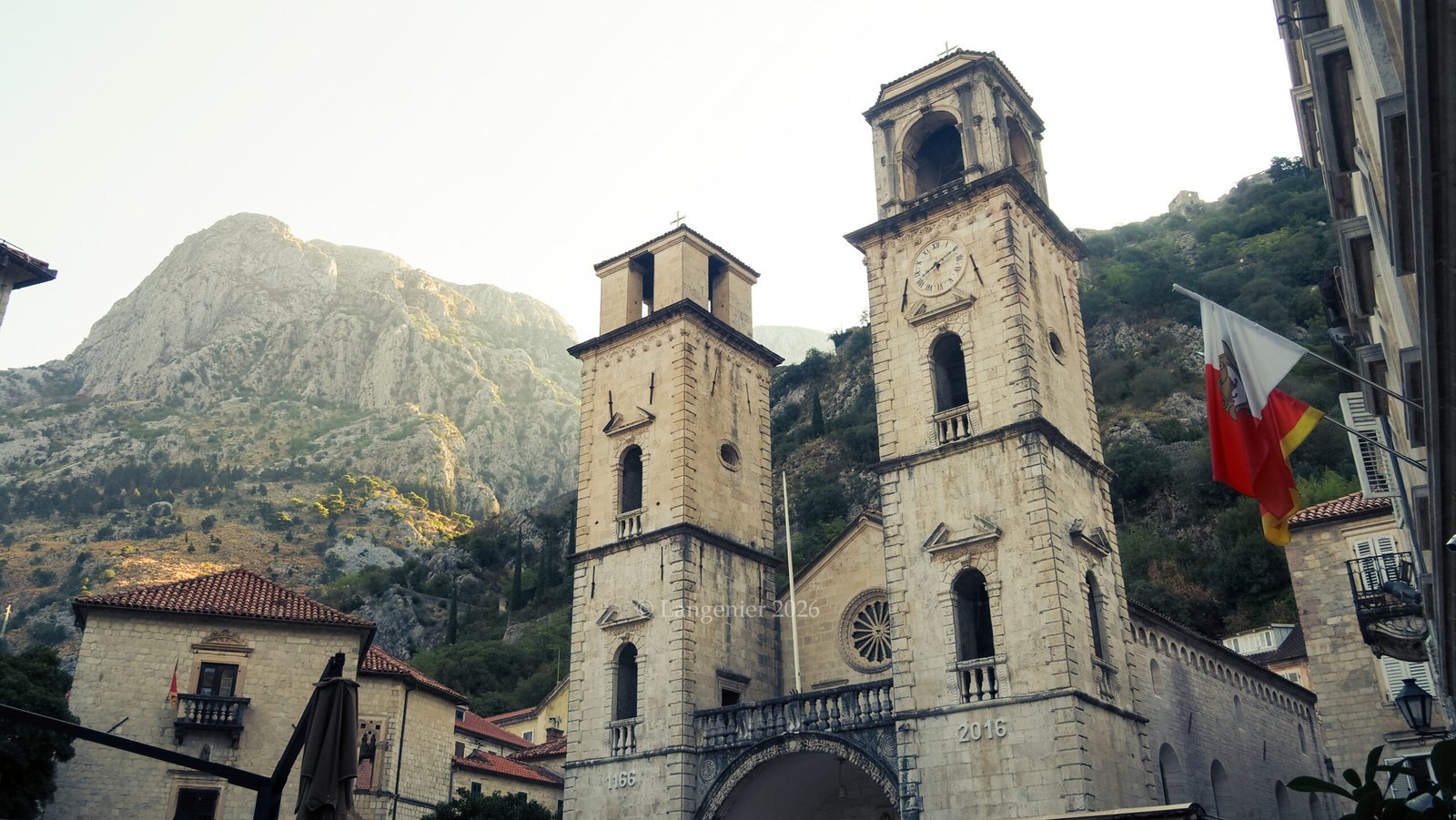 Twin bell towers of Saint Tryphon Cathedral in Kotor's old town, with mountain backdrop, Montenegro