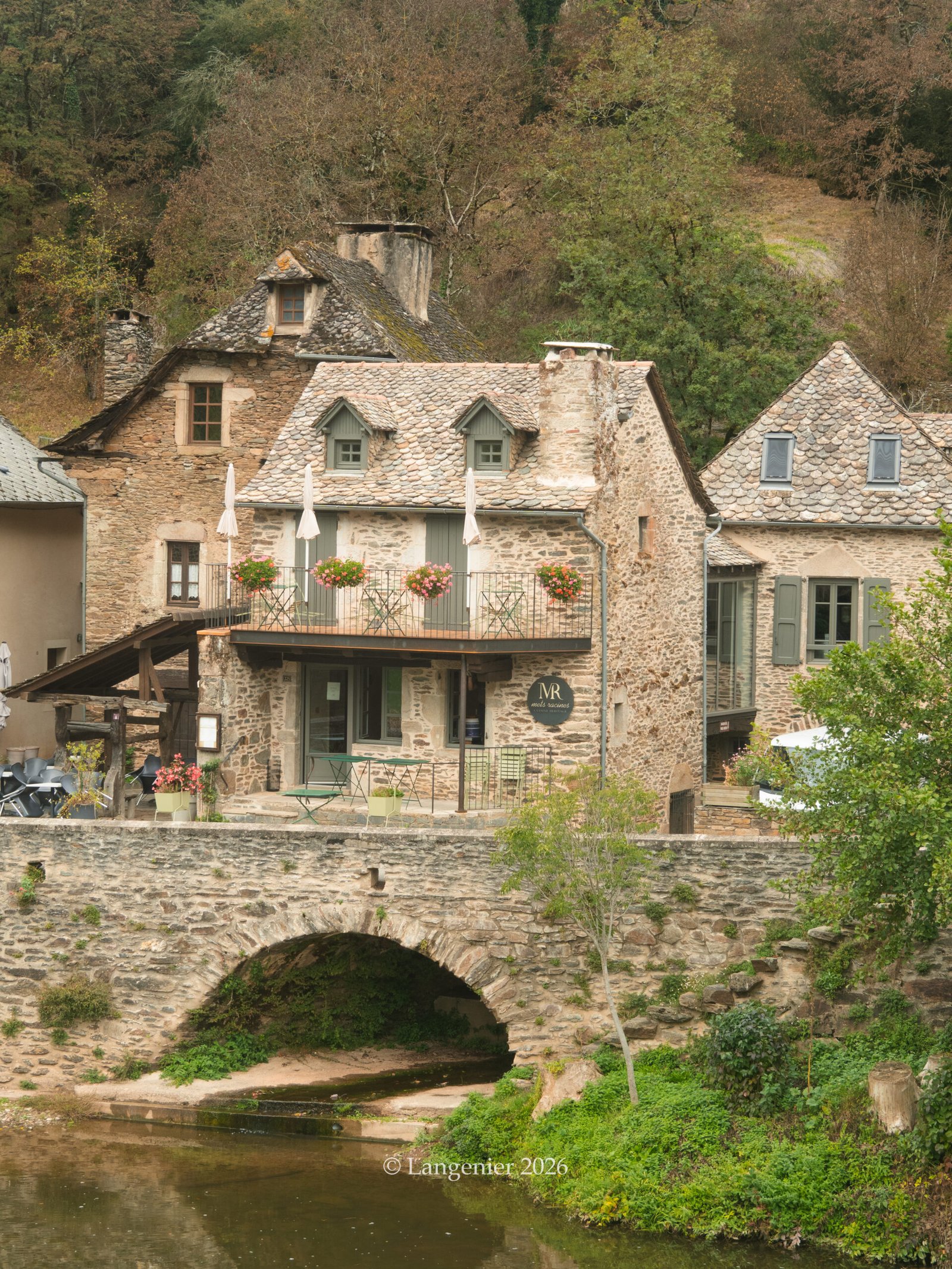 Stone houses and roofs blending into the green hills around the village of Conques, Aveyron, France