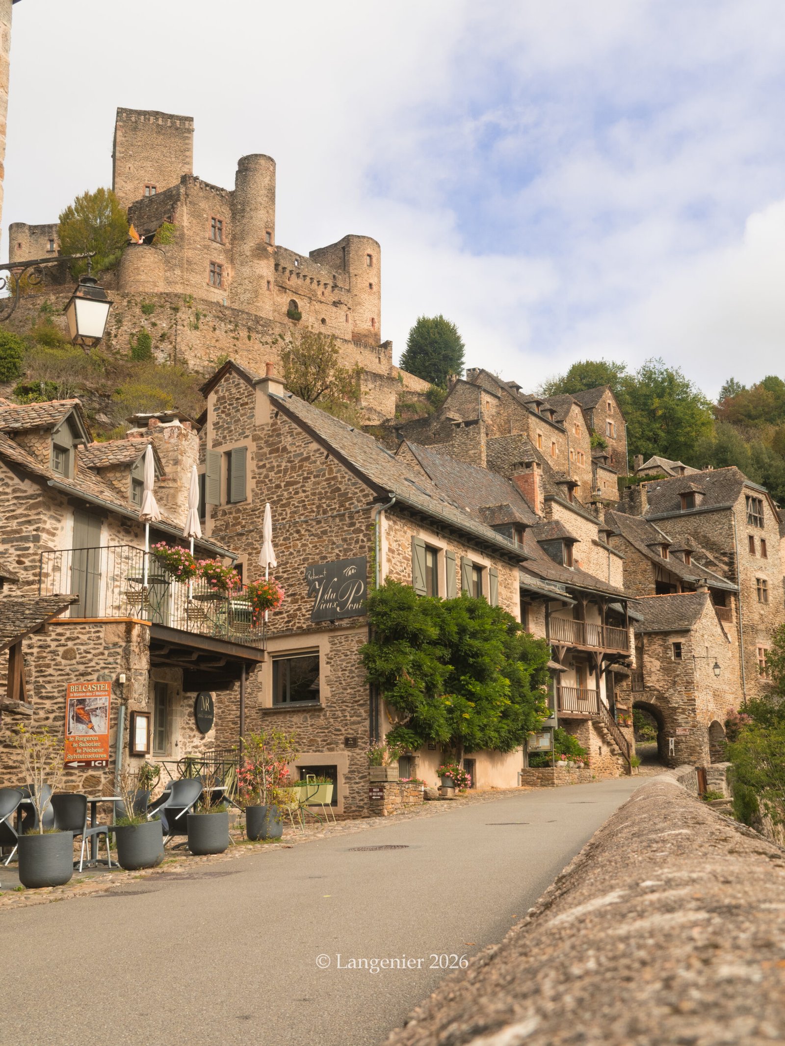 The main street of Belcastel, a picturesque French village, with several restaurants and small local shops along the street.